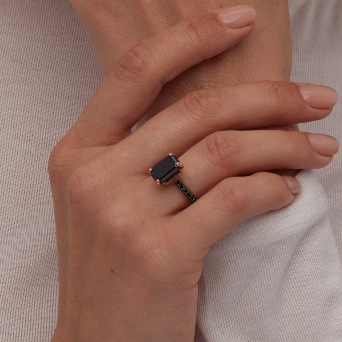 Oscura Magia emerald cut black diamond ring on a hand with a white sleeve