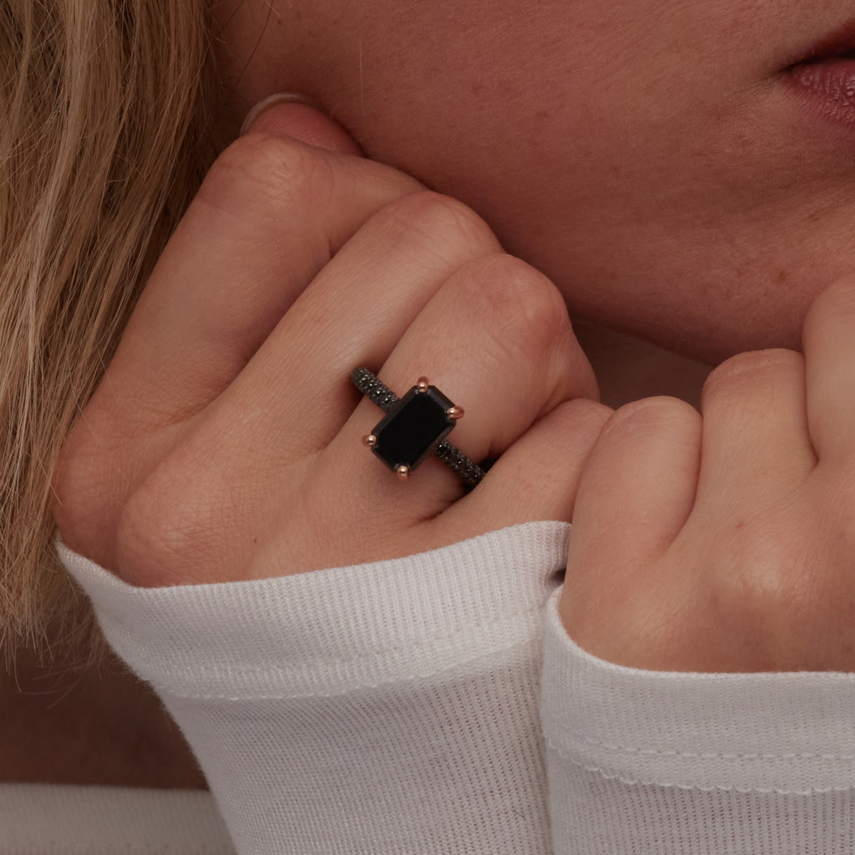 Emerald cut black diamond engagement ring, hand held to the face