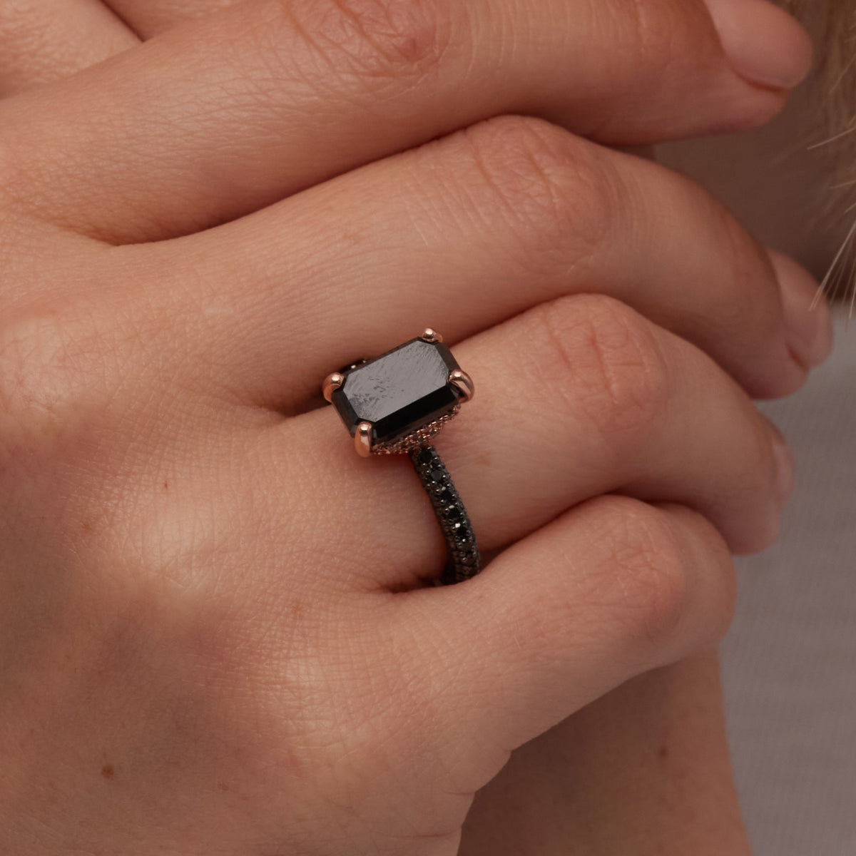Close-up of the emerald cut black diamond and black pavé band of Oscura Magia on the hand