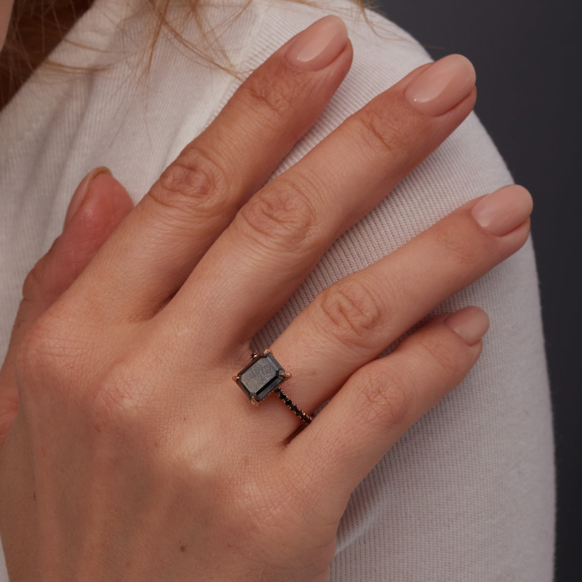 Oscura Magia emerald cut black diamond engagement ring worn on the ring finger