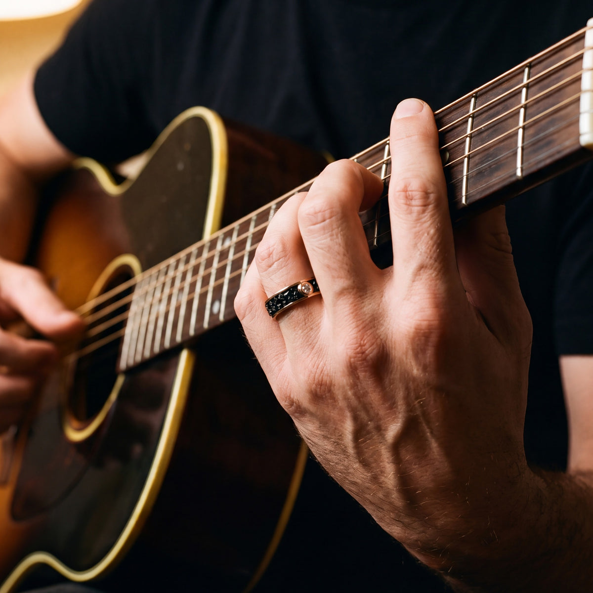 Accretion men's band in rose gold on a hand playing an acoustic guitar