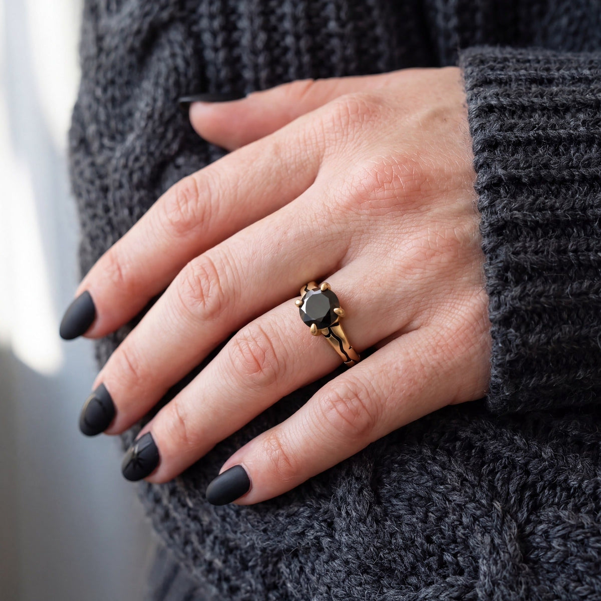 Kintsugi natural black diamond engagement ring in yellow gold worn on the hand, grey knit sweater