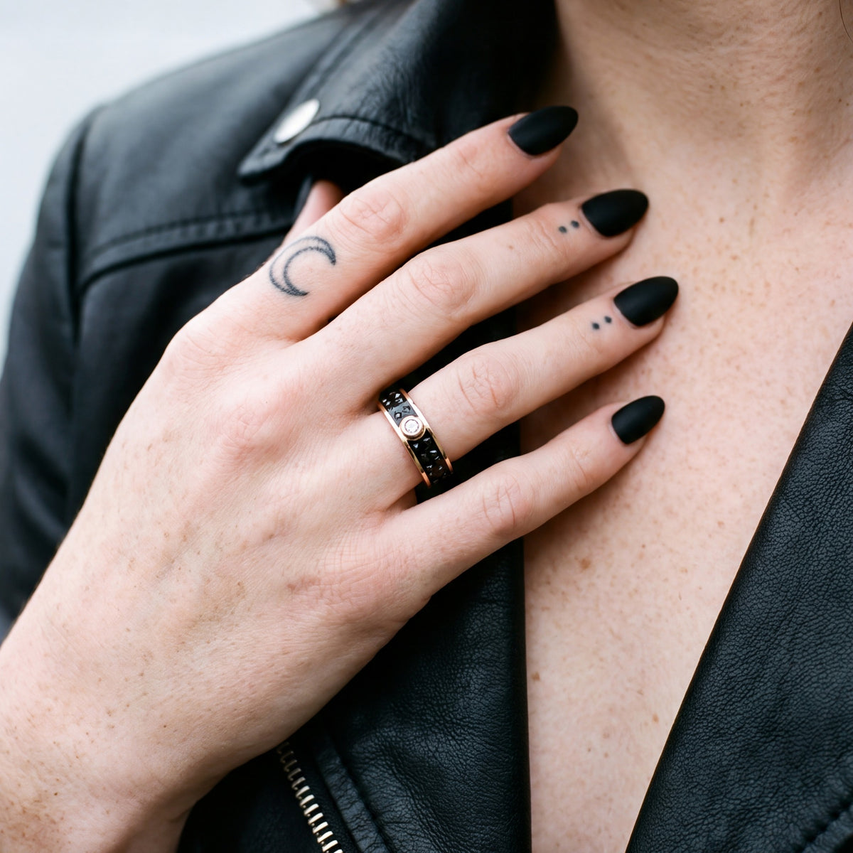 Accretion black diamond band on a woman's hand at the collar of a black leather jacket
