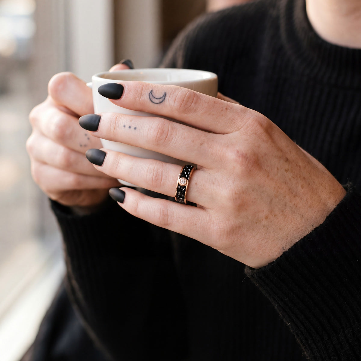 Accretion band in rose gold on a woman's hand holding an espresso cup