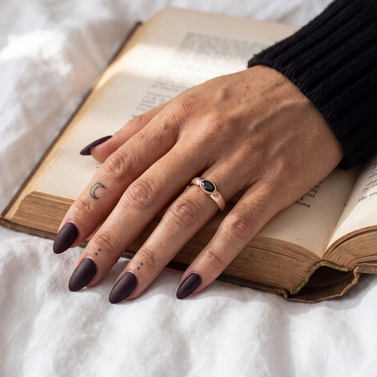 Rose gold Smoothen black diamond engagement ring with frosted shoulders on a hand resting on a book