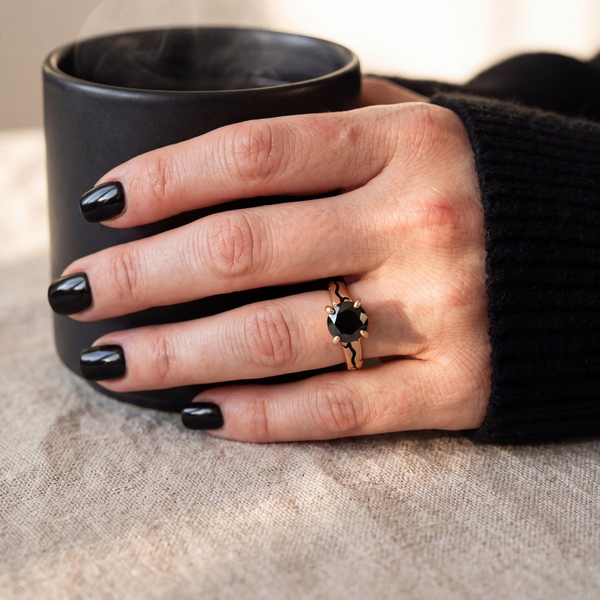 Kintsugi black diamond ring in rose gold on a hand holding a black mug