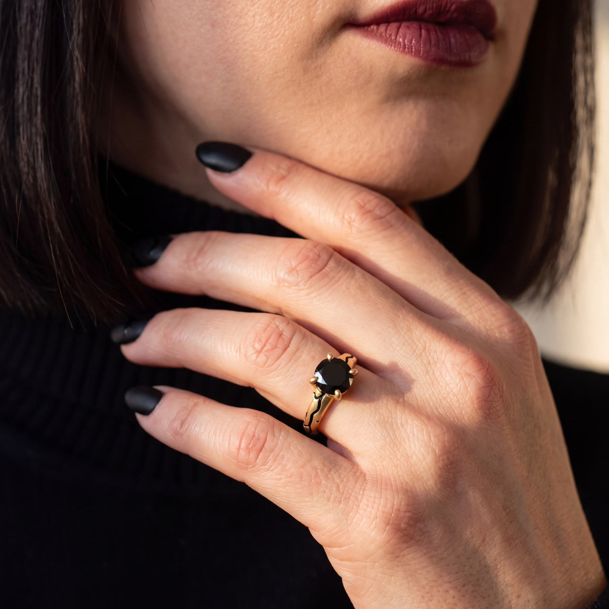 Kintsugi black diamond engagement ring in yellow gold, hand near the face