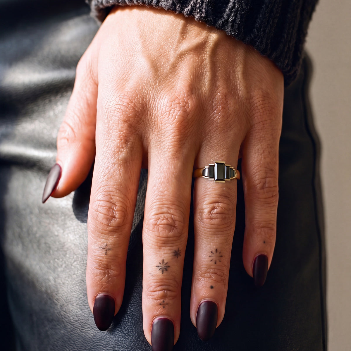 Pleiades graduated baguette natural black diamond ring worn on the hand in yellow gold