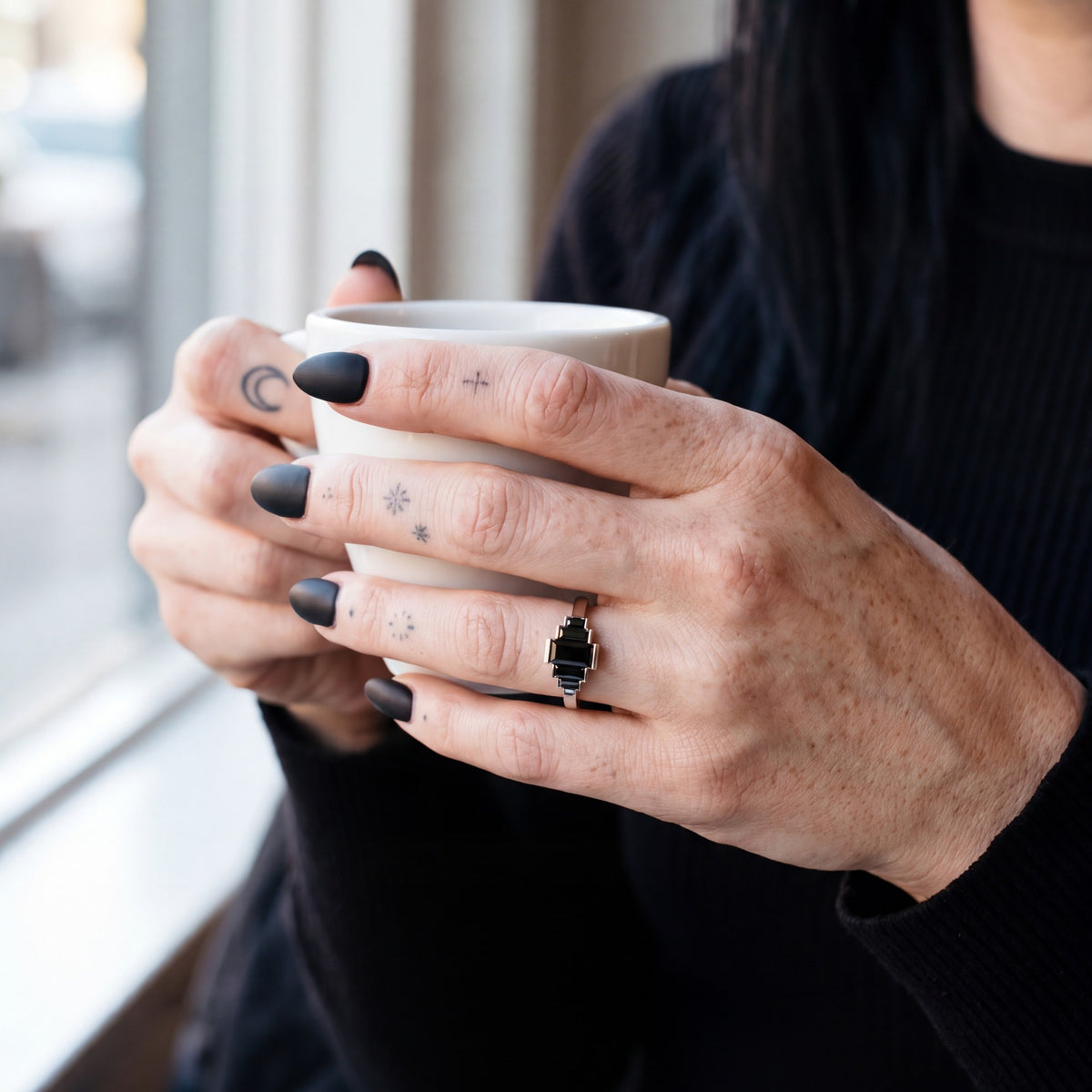 Pleiades graduated baguette natural black diamond ring in white gold, holding an espresso cup