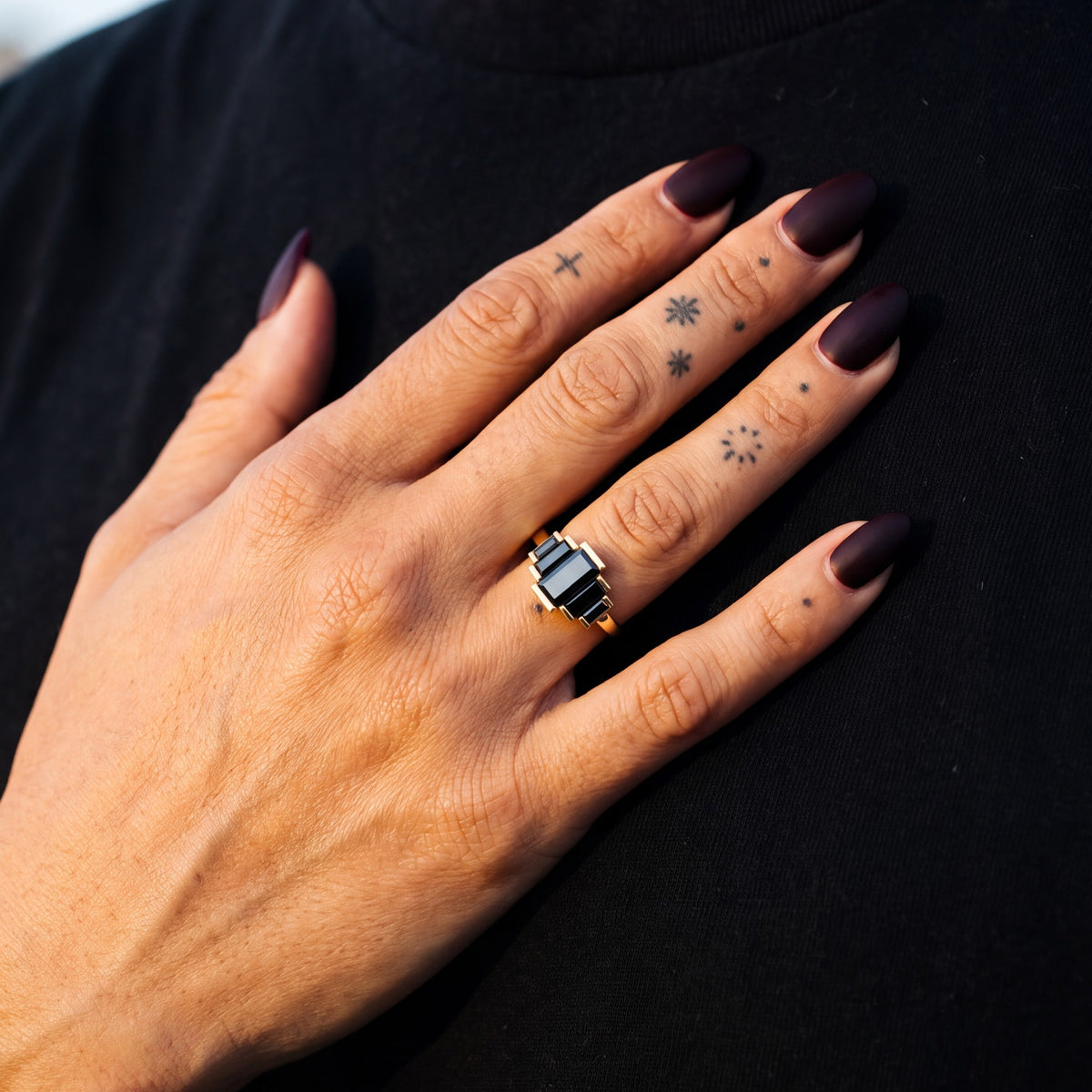 Pleiades graduated baguette natural black diamond ring in yellow gold, her hand on her partner's chest