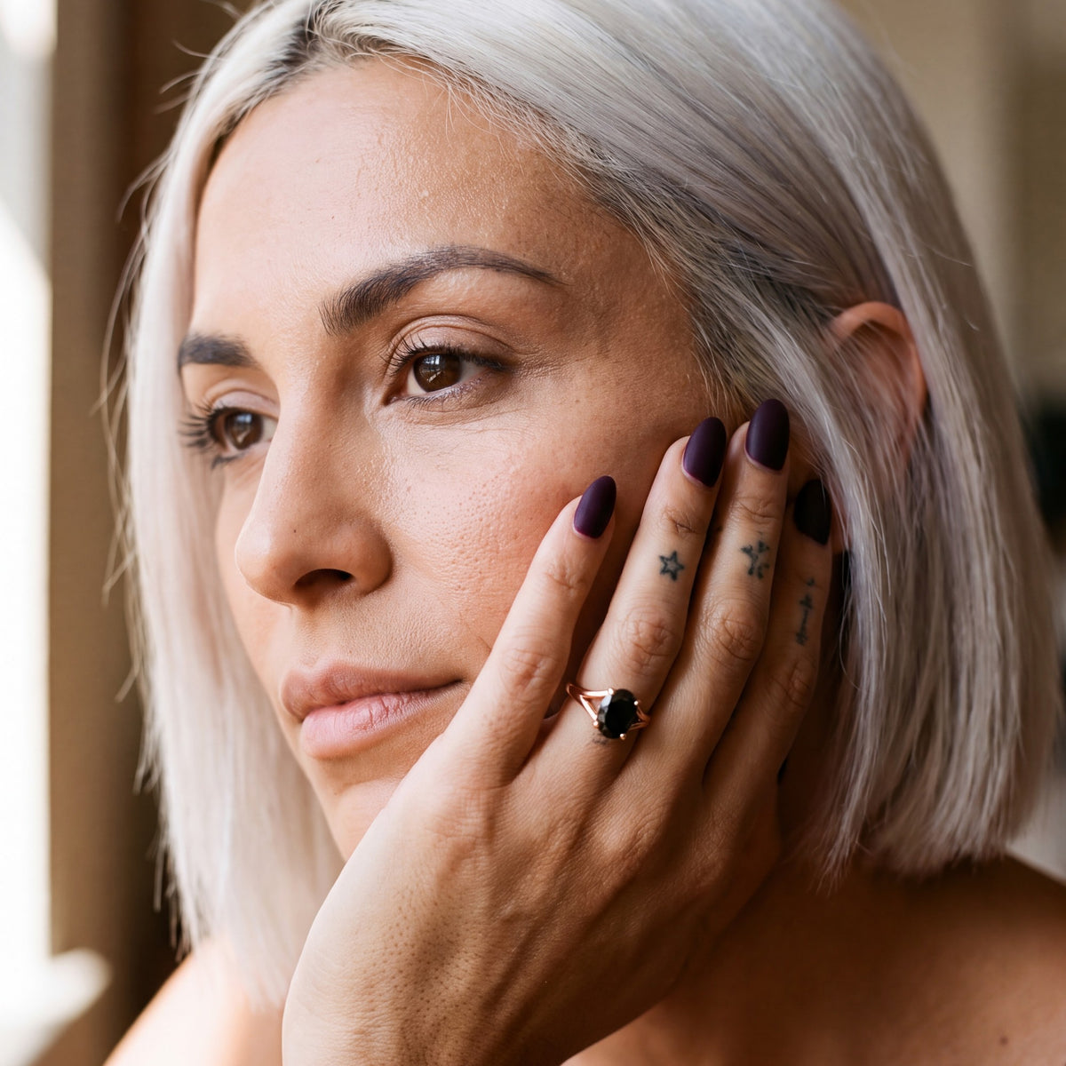 Melusine oval natural black diamond split shank ring in rose gold, her hand resting along her jaw