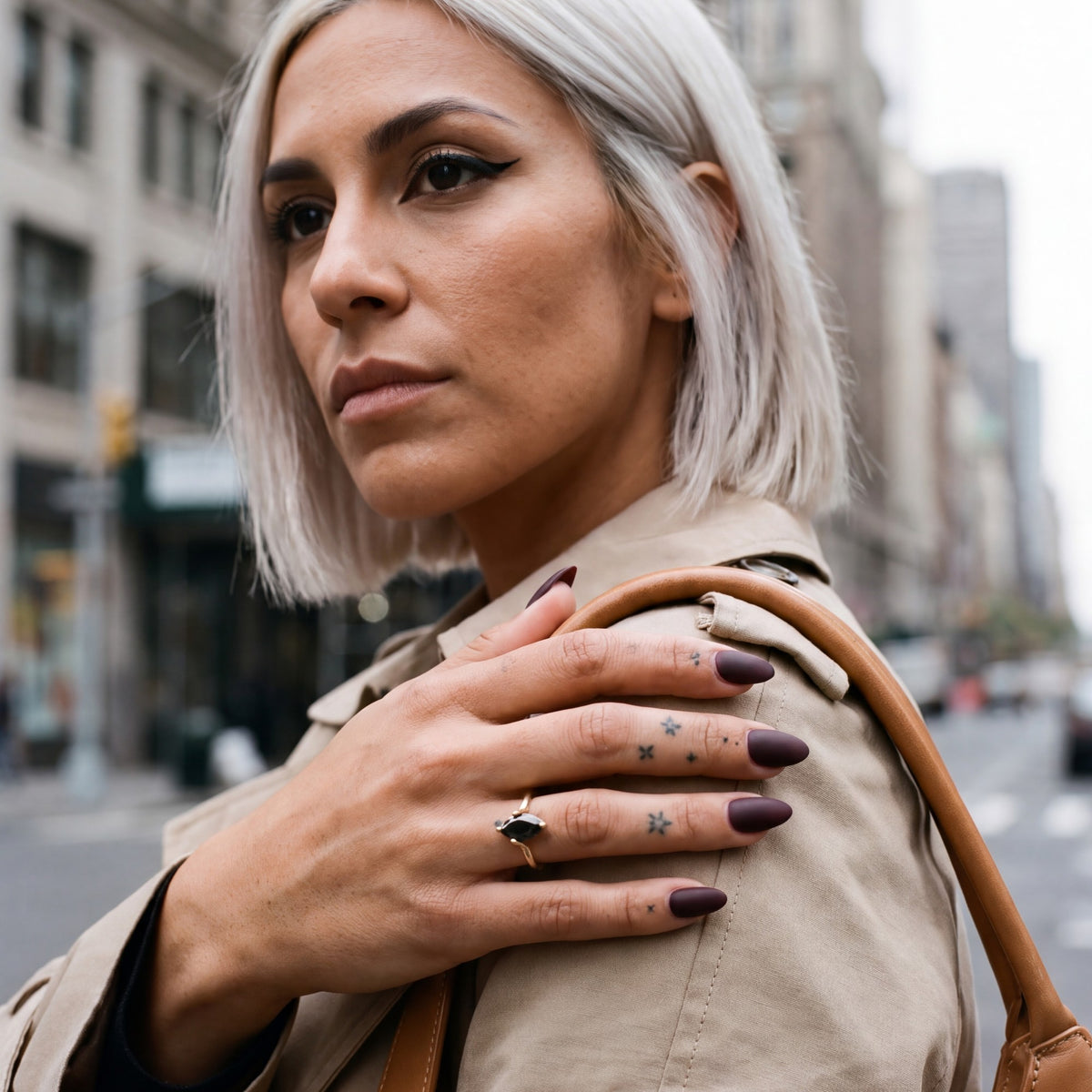 Phoenix marquise natural black diamond ring in yellow gold, her hand on the shoulder of a trench coat