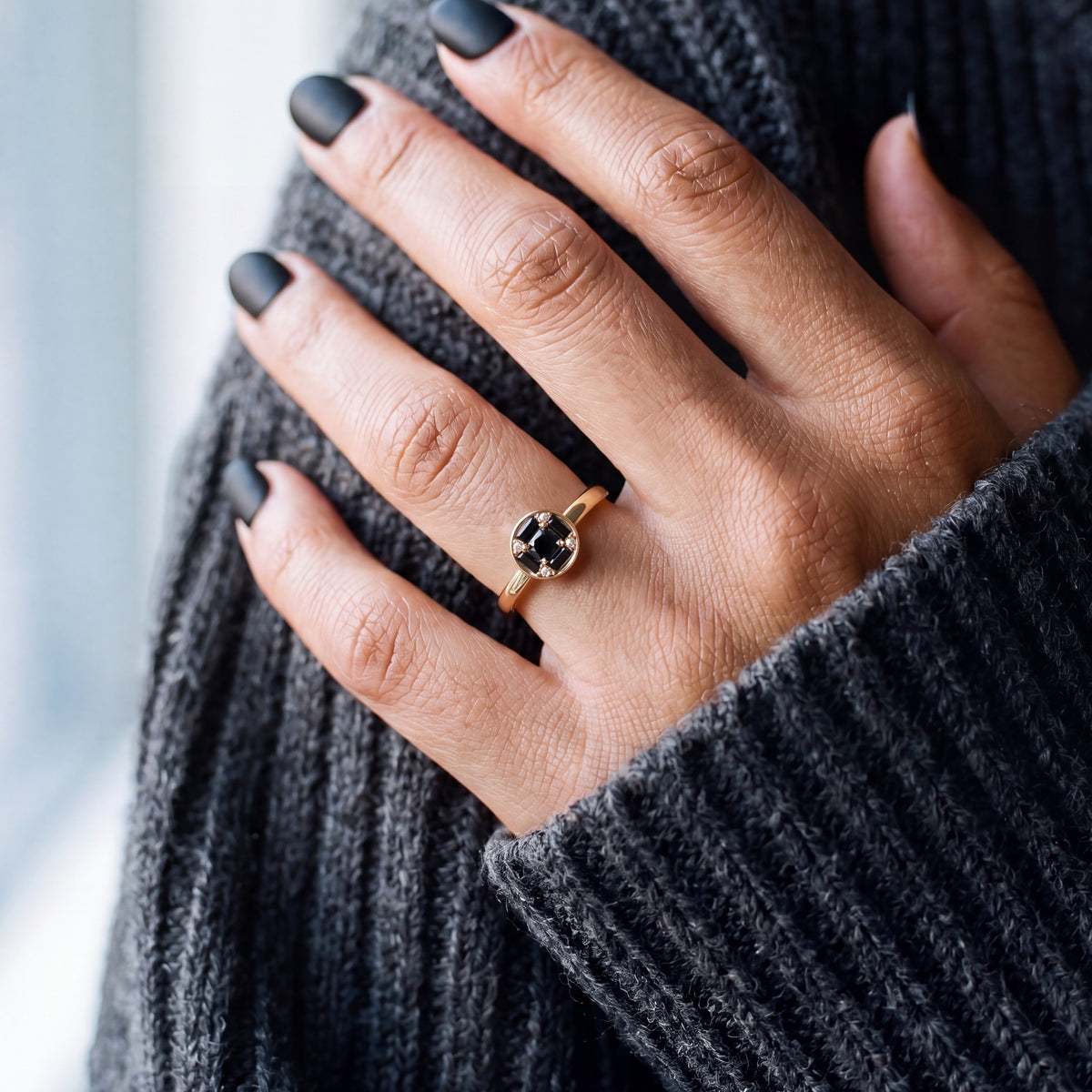 Polaris compass natural black diamond ring with baguettes and white diamond accents worn on the hand in yellow gold