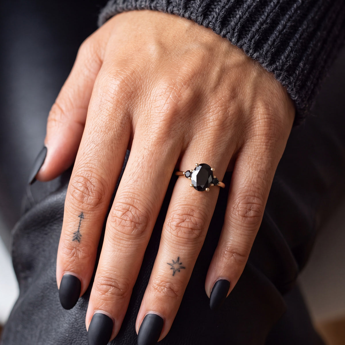 Centauri oval natural black diamond engagement ring with round side stones worn on the hand in yellow gold