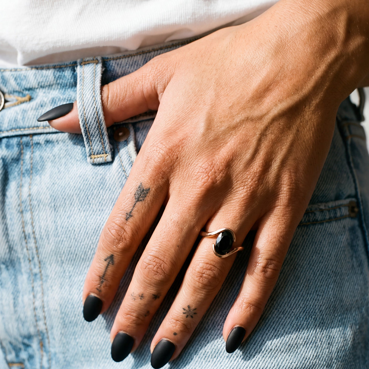 Selkie bypass oval natural black diamond engagement ring in rose gold, thumb in the pocket of light jeans