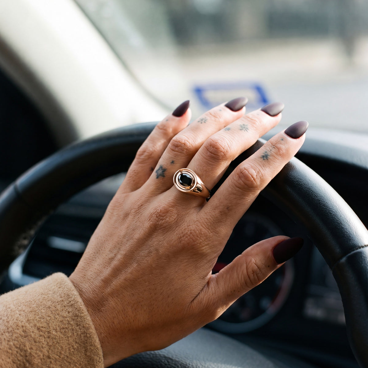 Algol east-west oval natural black diamond bezel ring in rose gold, her hand on a steering wheel