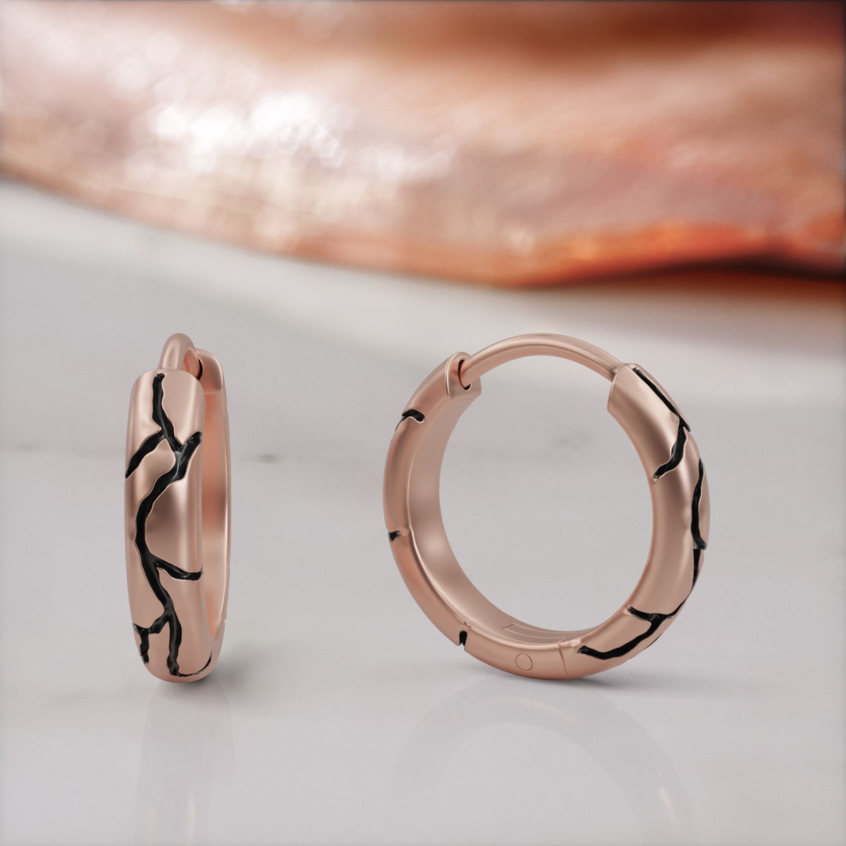 Kintsugi huggie earrings in rose gold, the pair, black enamel seams across the band