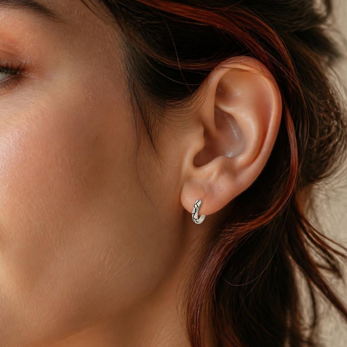 Kintsugi huggie earring in white gold, worn, close-up on the ear